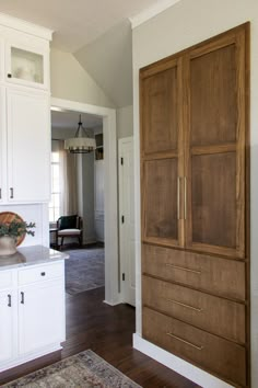 a large wooden cabinet sitting in the middle of a living room next to a kitchen