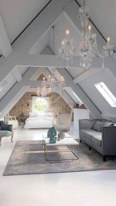 an attic bedroom with chandelier, couch and chair in it's center