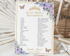 a purple and gold wedding seating plan with flowers on it, sitting next to a fan