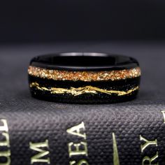 a black and gold ring sitting on top of a book