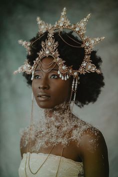 a woman wearing a tiara with pearls and beads on her head is looking at the camera