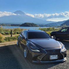 two cars parked next to each other on the side of a road near water and mountains