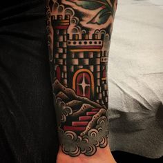 a man's arm with a castle tattoo on the left side of his arm