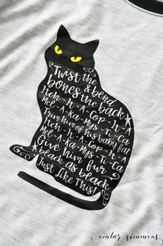 a black cat with yellow eyes on a white t - shirt