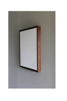 a white board mounted to the side of a wall with wood trim around it's edges