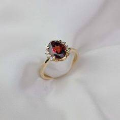 a red and white diamond ring sitting on top of a white cloth