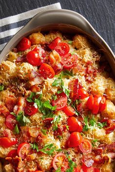 a casserole dish with tomatoes, cheese and parmesan bread on top