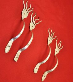 four silver metal handles on a red cloth with white designs in the shape of animals