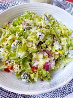 a white plate topped with lettuce and other vegetables next to a wooden table