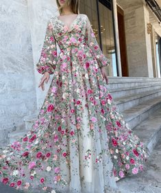 Imaginez-vous dans un magnifique jardin de fleurs sauvages, entouré de fleurs épanouies dans toutes les directions. Le soleil brille, la brise est douce et vous portez la magnifique robe en tulle Yana Garden. Cette robe incarne l'essence d'une garden-party fantaisiste, avec son tissu en tulle délicat, ses manches bouffantes ludiques et sa broderie florale complexe.

La silhouette A-line est universellement flatteuse, accentuant vos courbes et créant une forme de sablier de rêve. L'encolure en V profonde ajoute une touche d'élégance, tandis que la longue traîne ajoute une touche de glamour. Confectionnée à partir de tulle, d'élasthanne et de polyester de haute qualité, cette robe formelle pour femme a une coupe confortable et flatteuse, avec un soutien-gorge intégré pour un soutien accru. Spring Floral Print V-neck Gown, Feminine V-neck Gown For Spring, Feminine V-neck Spring Gown, Floor-length Floral Embellished Gown For Summer, Floor-length Floral Applique Gown For Garden Party, Spring Wedding Dress With Floral Design, Summer Wedding Maxi Dress With Floral Applique, Maxi Length Floral Applique Dress For Garden Party, Maxi Length Dress With Floral Applique For Garden Party