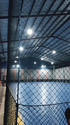 an indoor tennis court with lights on the ceiling and netted area for people to play