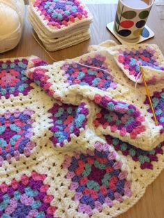 a crocheted blanket sitting on top of a table next to two mugs