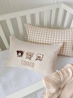 three teddy bears are embroidered onto the pillows in this baby's crib bed