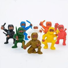 small toy figurines of different colors and sizes are posed in a row on a white surface