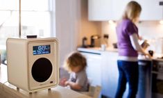 an alarm clock sitting on top of a counter next to a woman in a kitchen