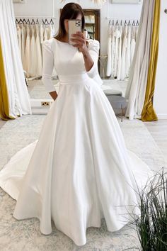 a woman taking a selfie while wearing a wedding dress in front of a mirror