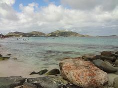 people are swimming in the ocean near some rocks