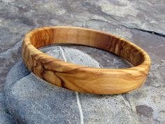 handmade Bracelet Bangle made out of fine olive wood Diameter inside 6,5 cm ( 2,56 inch) large ~1.5 cm ( 0,59 inch) the olive wood is finely sanded and oiled with olive oil naturally the grain of the olive wood can vary from item to item , but in any case you will get a olive wood bracelet with beautiful grain This bangles are turned by us from a piece of olive wood. Handmade in Portugal In our Shop you can find more earrings , rings and necklaces made out of olive wood ! Handmade Natural Color Bangle Bracelets, Handmade Natural Color Bangle Bracelet, Natural Color Bracelet Jewelry Gift, Natural Artisan Bracelet As Gift, Artisan Natural Color Bracelets As A Gift, Artisan Natural Color Bracelet As Gift, Natural Bangle Bracelets As Gift, Natural Color Bangle Bracelets As Gift, Natural Bangle Bracelets For Gifts