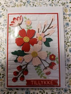 a card with flowers on it and the words tillykke written in red