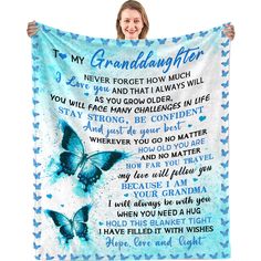 a woman holding up a blue and white blanket with the words to my granddaughter on it