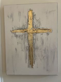 a painting of a cross on a white wall with gold paint and some black spots