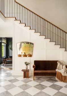 a living room filled with furniture next to a stair case and table on top of a checkered floor