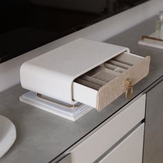 an open drawer on top of a counter next to a sink and toilet paper dispenser