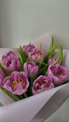 a bouquet of pink tulips is wrapped in white paper