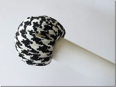 a black and white hat sitting on top of a wooden pole next to a wall