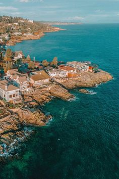 an aerial view of some houses on the shore by the ocean with clear blue water