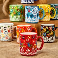 several colorful coffee mugs sitting on top of a wooden table next to each other