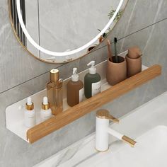 a bathroom counter with soap, lotion and other personal care items in front of a round mirror