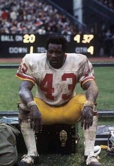 a football player sitting on the sidelines with his foot propped up in front of him