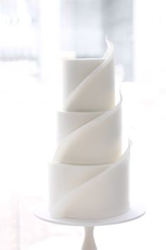 a three tiered white cake sitting on top of a table next to a window