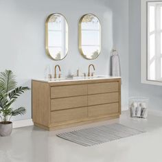 a white bathroom with two mirrors above the sinks and a rug in front of it