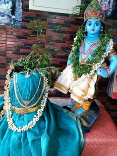 there is a blue statue sitting next to a vase with greenery on the table