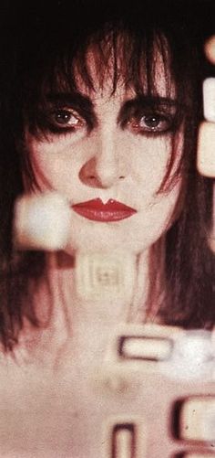 a woman with dark hair and red lipstick holding up a cell phone to her face