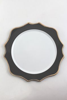 an empty black and gold plate on a white surface