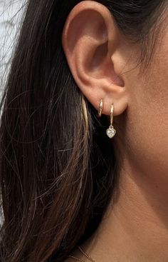 a close up of a person's ear wearing gold earrings and a chain necklace