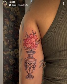 a woman's arm with a vase and flowers tattoo on the left side of her arm