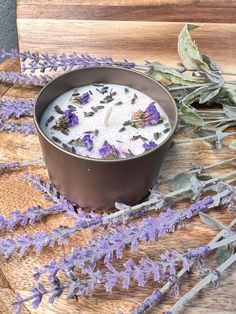 a bowl filled with lavender flowers sitting on top of a wooden table next to dried plants