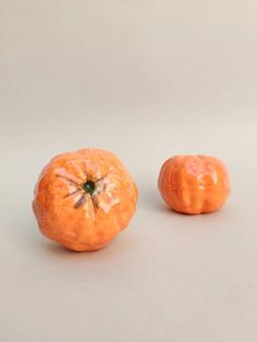 two oranges sitting next to each other on a white surface with no one around them