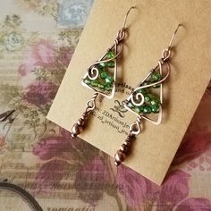 the earrings are made with green glass and silver wire, on top of a card