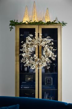 a christmas wreath is displayed in front of a lighted display case with lights on it