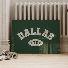 a green sign with the word dallas on it next to a pair of newspapers