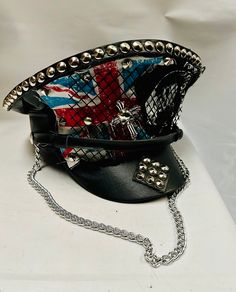 This is a black leatherette captain hat. Well made to a high standard. It has plenty of eye catching detail including metal studs, safety pins and Union Jack  , please refer to photos . It also has a metal chain, This is a size 59 cm which fits most size heads. No two hats are created the same. Individual and unique  Thank you for looking Black Steampunk Top Hat For Alternative Fashion, Punk Style High Crown Hat For Cosplay, Edgy Black Hat For Alternative Fashion, Black Alternative Style Hats For Alternative Fashion, Black Punk Costume Hats And Headpieces, Black Punk Hat For Cosplay, Punk Style Party Cap Hat, Black Top Hat For Halloween Alternative Fashion, Black Punk Top Hat For Alternative Fashion