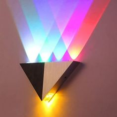 a colorful light is shining on the side of a wooden wall mounted clock with triangular shapes