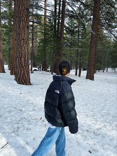 a person walking in the snow near some trees