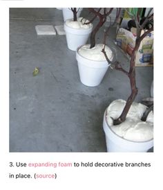 three white buckets filled with cream sitting on top of a cement floor next to a tree