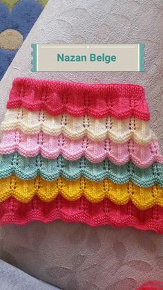 there is a crocheted blanket with many colors on the bottom and one has a name tag that says nazan belge